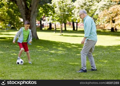 family, generation, game, sport and people concept - happy grandfather and grandson playing football at summer park