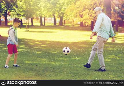family, generation, game, sport and people concept - happy grandfather and grandson playing football at summer park. old man and boy playing football at summer park