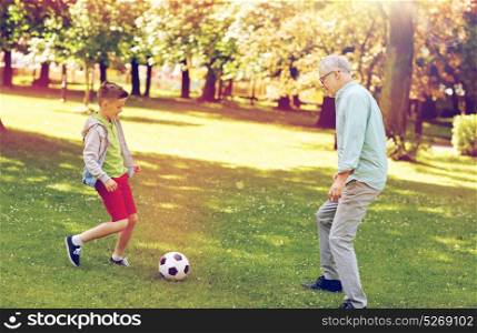 family, generation, game, sport and people concept - happy grandfather and grandson playing football at summer park. old man and boy playing football at summer park