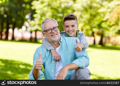 family, generation, gesture and people concept - happy grandfather and grandson showing thumbs up at summer park