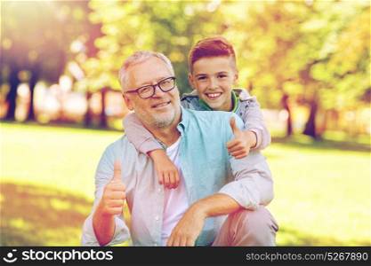 family, generation, gesture and people concept - happy grandfather and grandson showing thumbs up at summer park. grandfather and boy showing thumbs up at summer