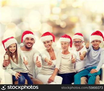 family, generation, gesture, holidays and people concept - happy family in santa helper hats showing thumbs up over lights background
