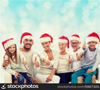 family, generation, gesture, holidays and people concept - happy family in santa helper hats showing thumbs up over blue lights background