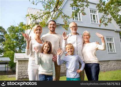 family, generation, gesture, home and people concept - happy family standing in front of house waving hands outdoors