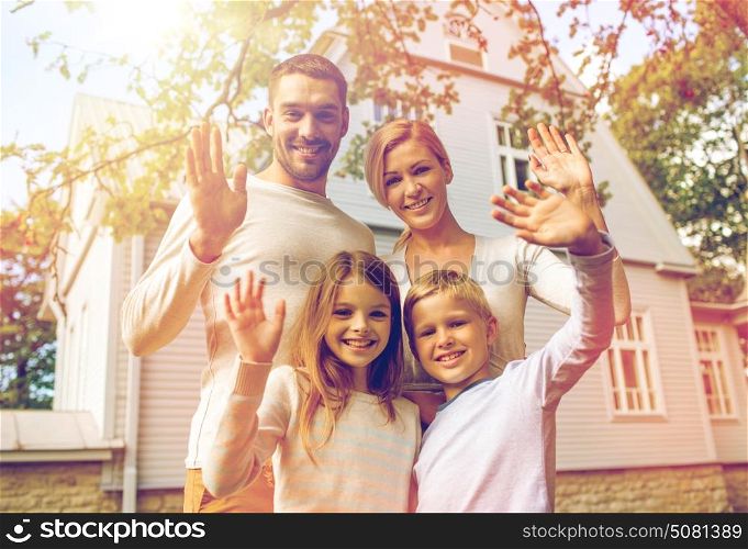 family, generation, home, gesture and people concept - happy family standing in front of house waving hands outdoors. happy family in front of house outdoors