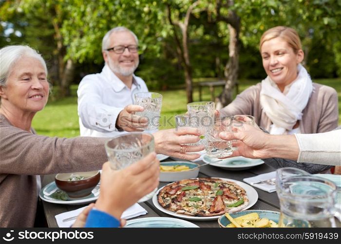 family, generation, home, holidays and people concept - happy family having dinner and clinking glasses in summer garden