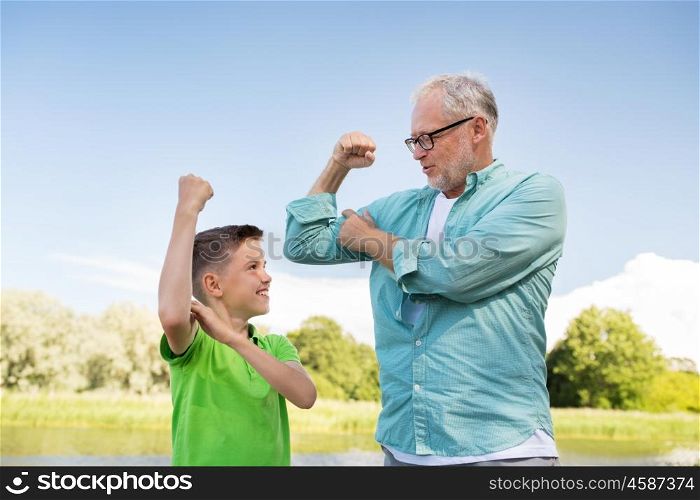 family, generation, power and people concept - happy grandfather and grandson showing muscles