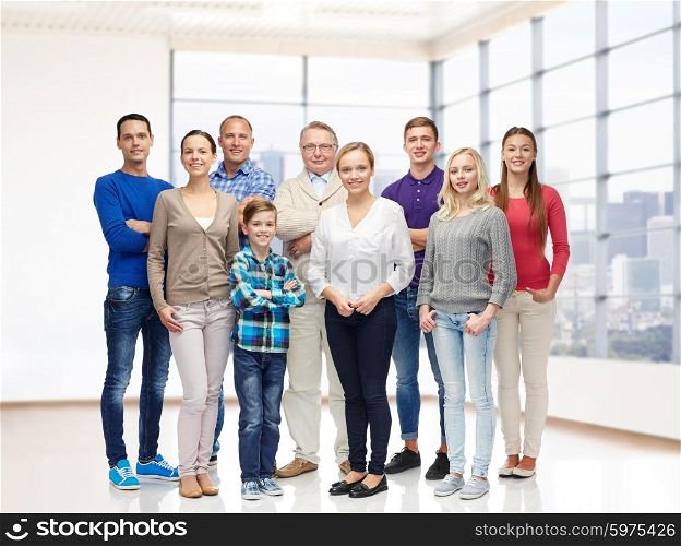 family, generation, real estate and people concept - group of smiling men, women and boy over empty apartment or office room background