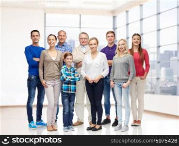 family, generation, real estate and people concept - group of smiling men, women and boy over empty apartment or office room background
