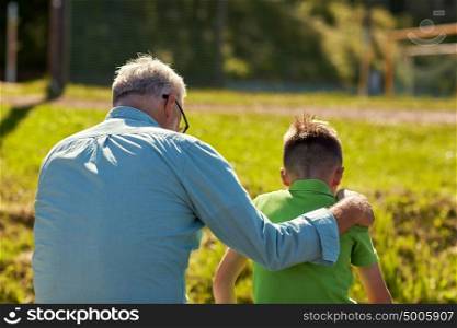 family, generation, relations and people concept - grandfather and grandson hugging outdoors. grandfather and grandson hugging outdoors