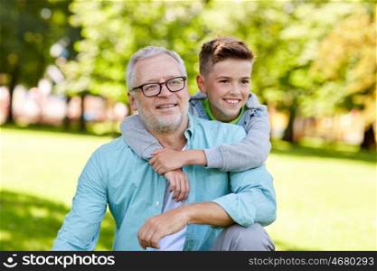 family, generation, relations and people concept - happy grandfather and grandson hugging at summer park