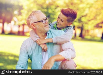 family, generation, relations and people concept - happy grandfather and grandson hugging at summer park. grandfather and grandson hugging at summer park