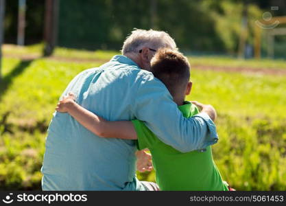 family, generation, relations and people concept - happy grandfather and grandson hugging outdoors. grandfather and grandson hugging outdoors
