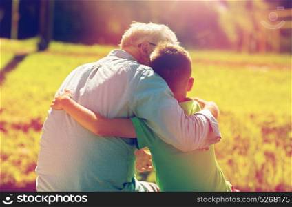 family, generation, relations and people concept - happy grandfather and grandson hugging outdoors. grandfather and grandson hugging outdoors