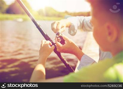 family, generation, summer holidays and people concept - boy and grandfather with fishing rod or spinning on river or lake berth. boy and grandfather with fishing rod on river