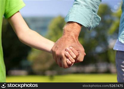 family, generation, support and people concept - senior man and child holding hands outdoors. senior man and child holding hands