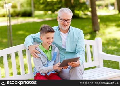 family, generation, technology and people concept - happy grandfather and grandson with tablet pc computer at summer park