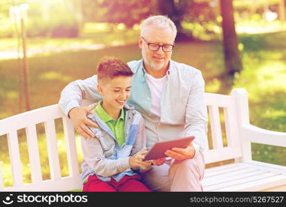 family, generation, technology and people concept - happy grandfather and grandson with tablet pc computer at summer park. grandfather and boy with tablet pc at summer park