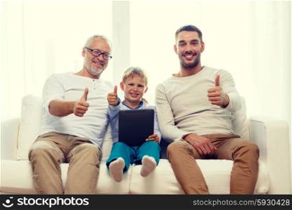 family, generation, technology and people concept - smiling father, son and grandfather sitting on couch with tablet pc computer showing thumbs up gesture at home