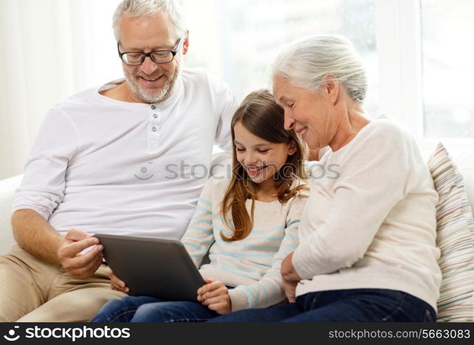 family, generation, technology and people concept - smiling grandfather, granddaughter and grandmother with tablet pc computer sitting on couch at home