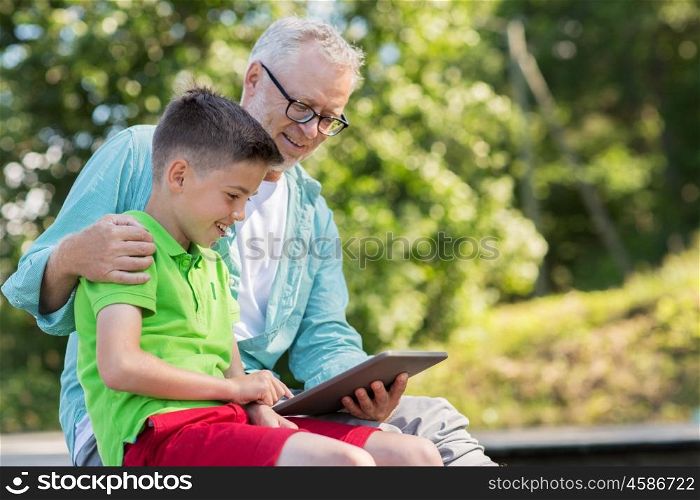 family, generation, technology, communication and people concept - happy grandfather and grandson with tablet pc computer outdoors