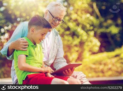 family, generation, technology, communication and people concept - happy grandfather and grandson with tablet pc computer outdoors. happy grandfather and boy with tablet pc outdoors