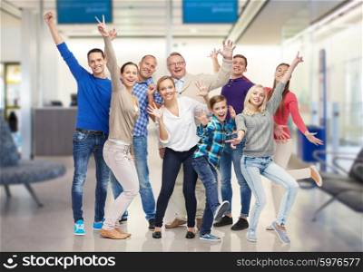 family, generation, travel, tourism and people concept - group of happy men, women and boy having fun and waving hands over airport waiting room background