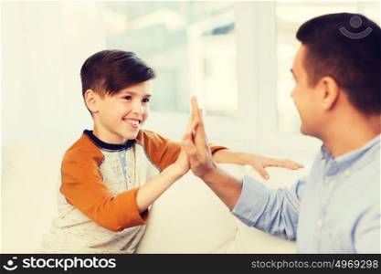 family, gesture, fatherhood, generation and people concept - happy father and son doing high five at home. happy father and son doing high five at home