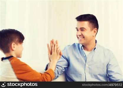 family, gesture, fatherhood, generation and people concept - happy father and son doing high five at home. happy father and son doing high five at home