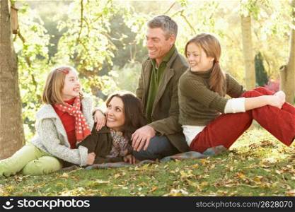 Family Group Relaxing Outdoors In Autumn Landscape