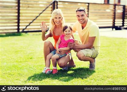 family, happiness, adoption, gesture and people concept - happy family waving hand outdoors