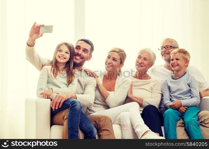 family, happiness, generation and people concept - happy family sitting on couch and making selfie with smartphone at home