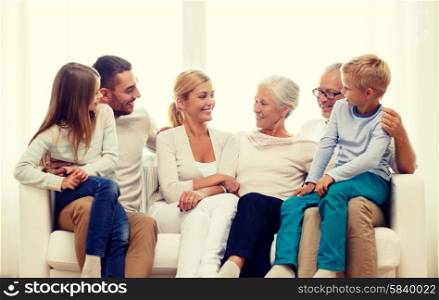 family, happiness, generation and people concept - happy family sitting on couch at home