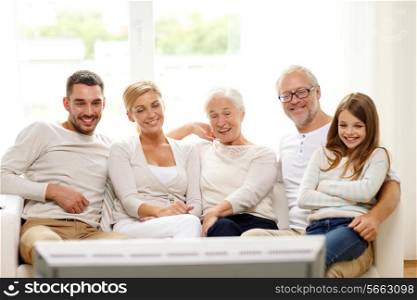 family, happiness, generation and people concept - happy family sitting on sofa and watching tv at home