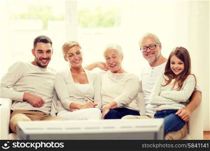 family, happiness, generation and people concept - happy family sitting on sofa and watching tv at home