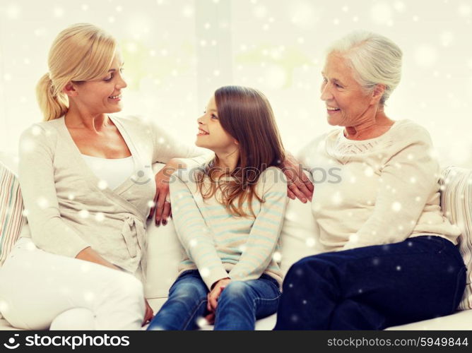 family, happiness, generation and people concept - smiling mother, daughter and grandmother sitting on couch at home