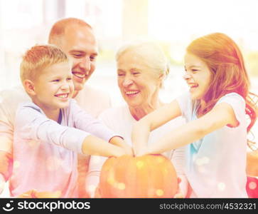 family, happiness, generation, holidays and people concept - happy family making halloween pumpkins at home