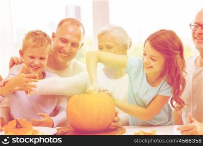 family, happiness, generation, holidays and people concept - happy family making halloween pumpkins at home
