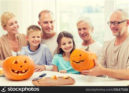 family, happiness, generation, holidays and people concept - happy family making halloween pumpkins at home
