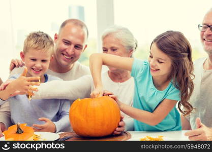 family, happiness, generation, holidays and people concept - happy family making halloween pumpkins at home