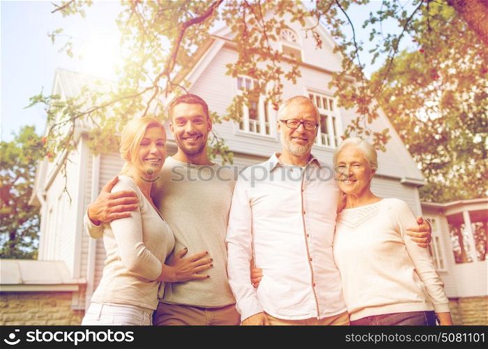 family, happiness, generation, home and people concept - happy family standing in front of house outdoors. happy family in front of house outdoors