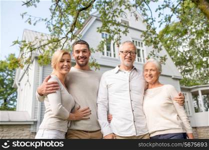 family, happiness, generation, home and people concept - happy family standing in front of house outdoors