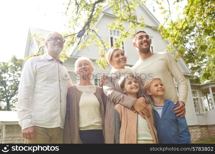 family, happiness, generation, home and people concept - happy family standing in front of house outdoors