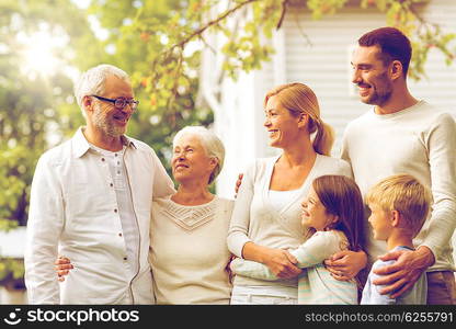 family, happiness, generation, home and people concept - happy family standing in front of house outdoors