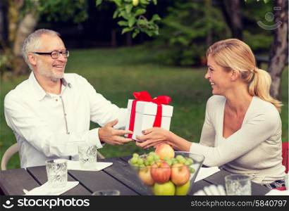 family, happiness, generation, home and people concept - happy family with gift box having holiday dinner outdoors