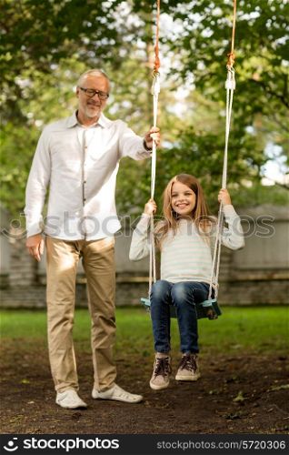 family, happiness, generation, home and people concept - happy grandfather and granddaughter swinging on teeterboard outdoors