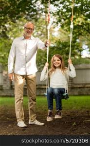 family, happiness, generation, home and people concept - happy grandfather and granddaughter swinging on teeterboard outdoors