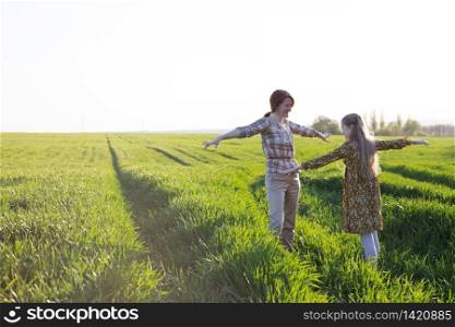 family - happy mother and daughter on a field on the sunset