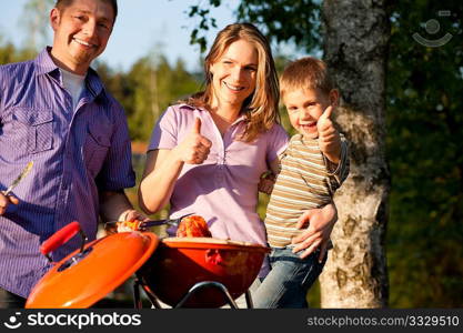 Family having a barbecue party, mother father and son standing around the bbq grill