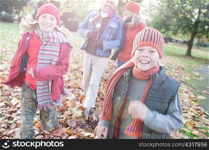 Family having fun in park, walking through autumn leaves